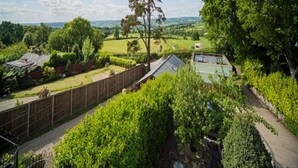 Un barrio residencial con jardín cercado, un árbol grande y vistas al campo.
