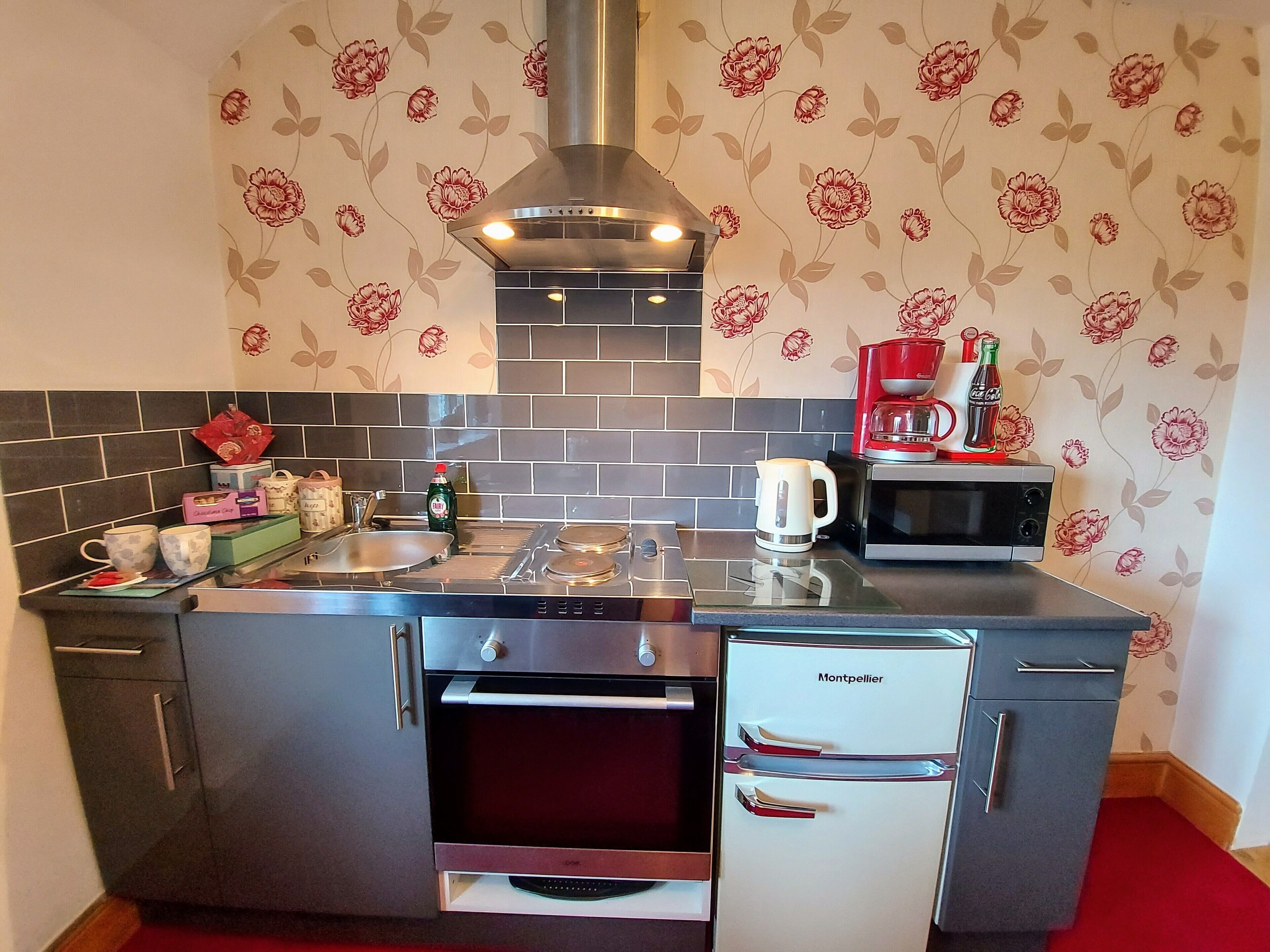 A modern kitchen with a stainless steel stove, a built-in oven, a coffee maker, and a refrigerator.