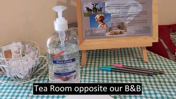 A table with a sign for 'Diamond's Tea Room & Ice Cream Parlour', a bottle of Pure-Klenz hand sanitizer, and a tray with tea bags.