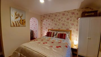 A bedroom with a bed, a wardrobe, and a floral wallpaper.