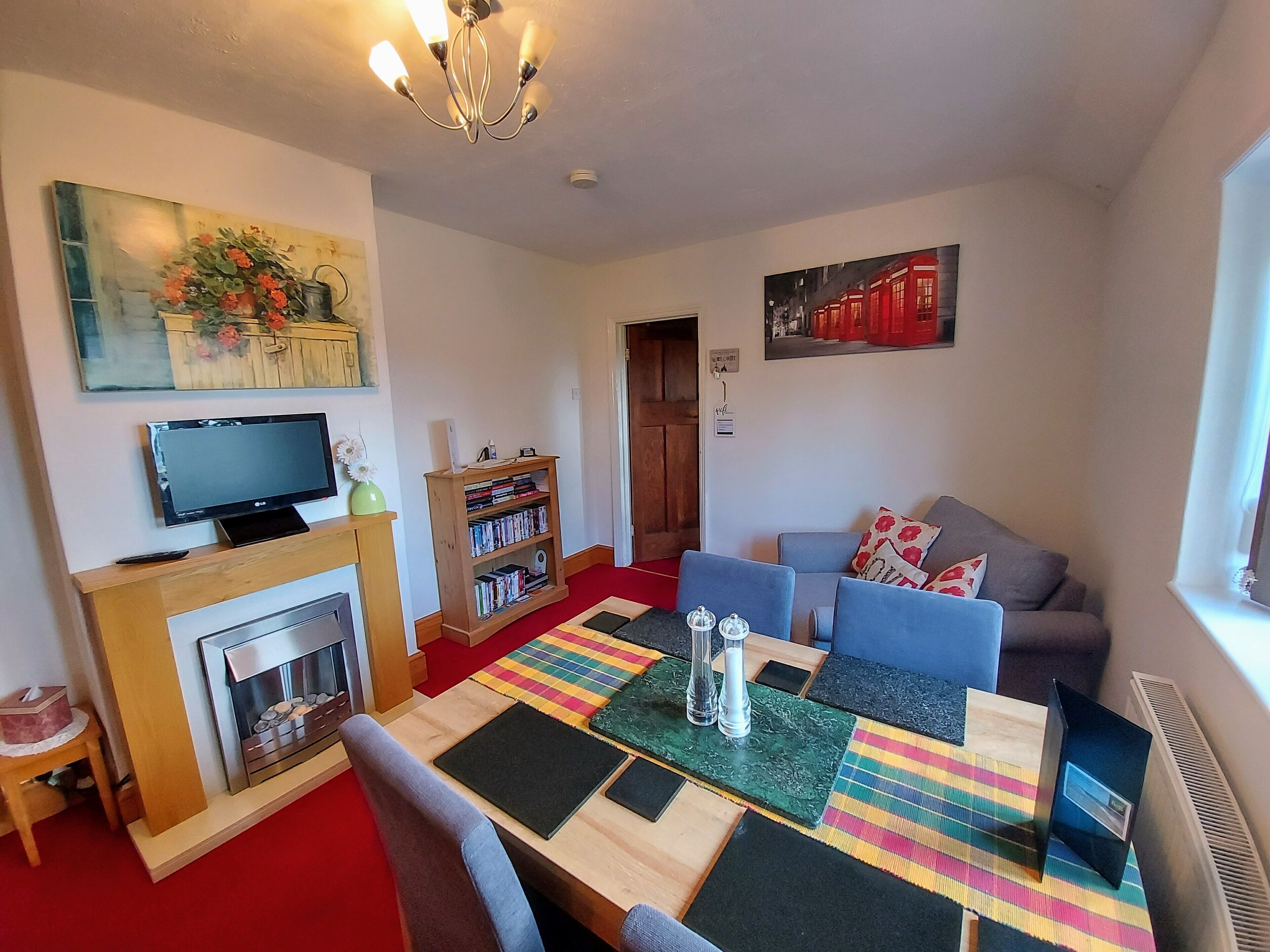 A living room with a fireplace, a television, a bookshelf, a sofa, and a colorful rug.