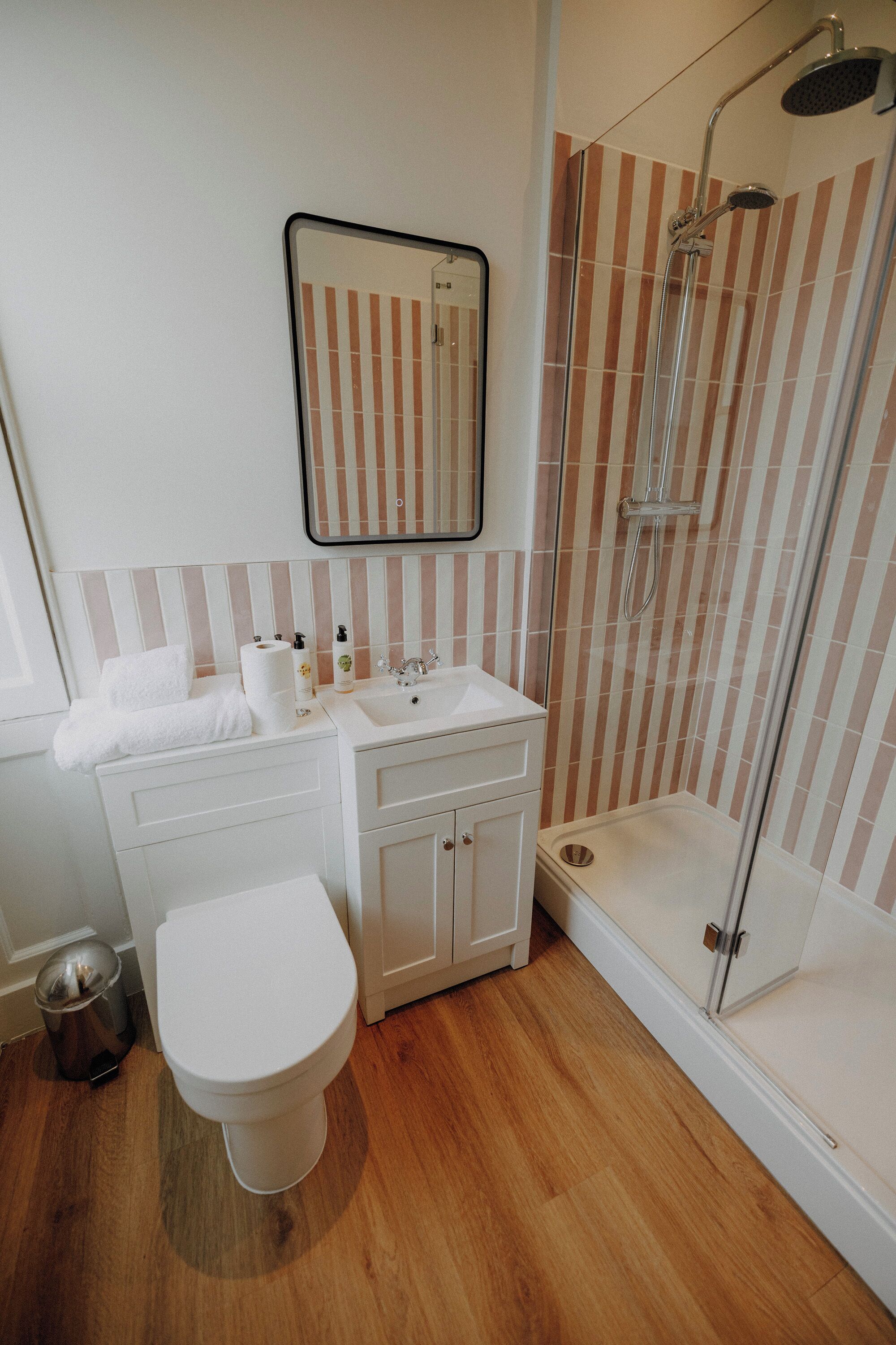 A bathroom with a white toilet, a sink with a mirror above it, and a shower area with a glass door.