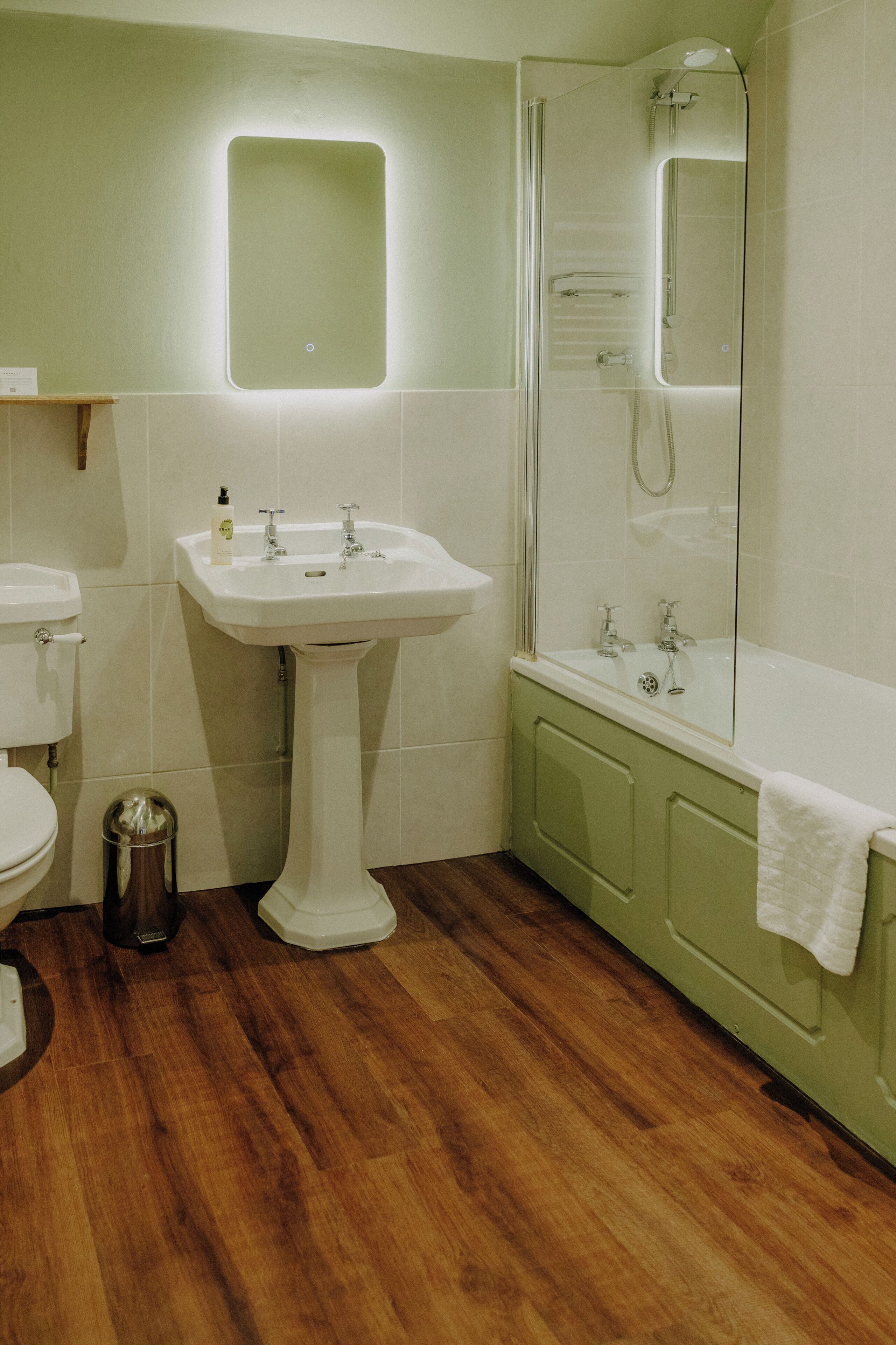 A bathroom with a pedestal sink, toilet, and a bathtub with a shower.