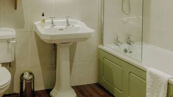 A bathroom with a pedestal sink, toilet, and a bathtub with a shower.