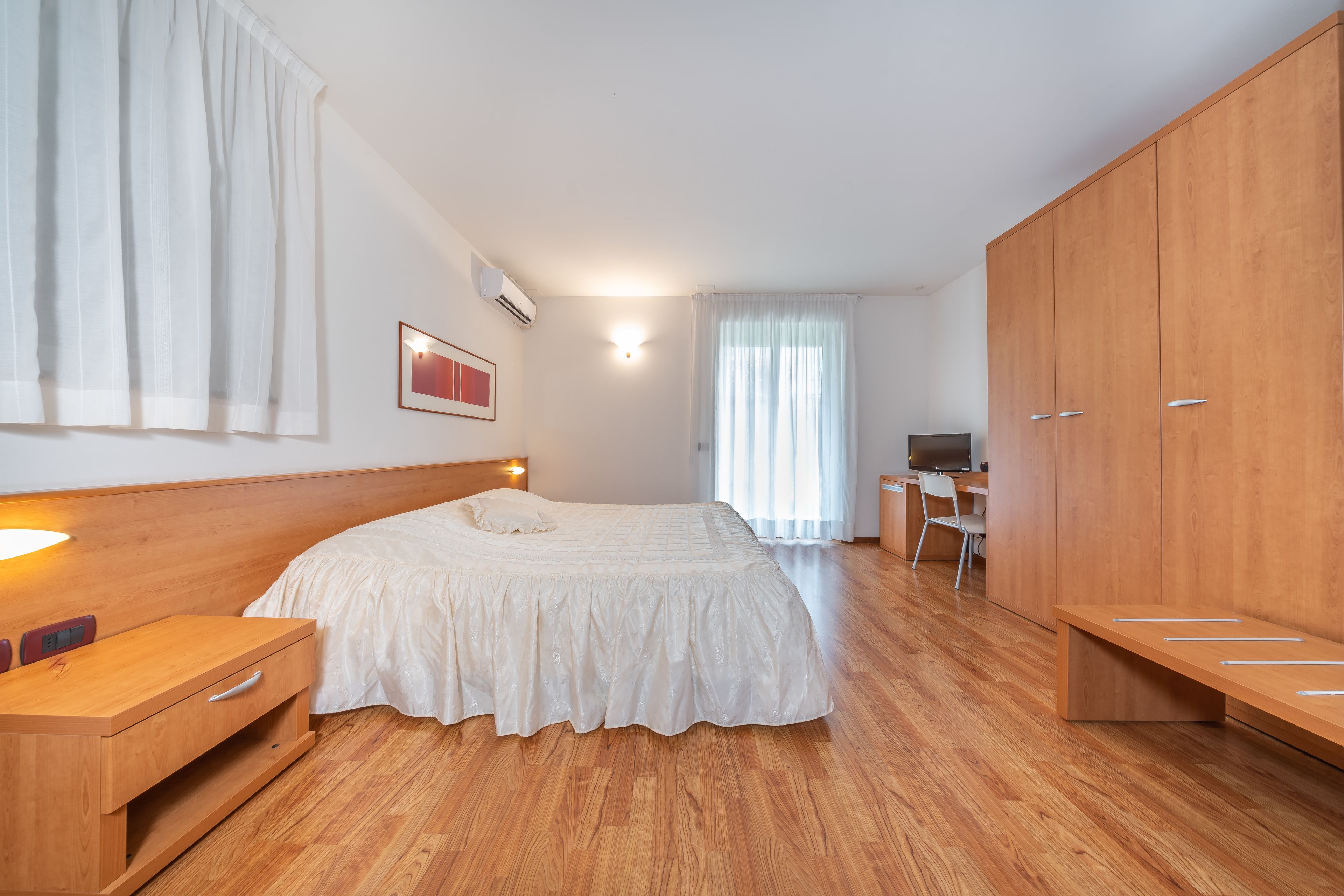 A bedroom with a wooden bed, a desk, and a wardrobe.