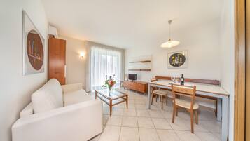 A modern living room with a sofa, coffee table, and dining area with chairs and a table.