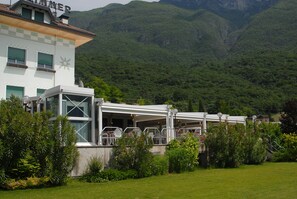 Un restaurante con terraza al aire libre, rodeado de exuberante vegetación y montañas.