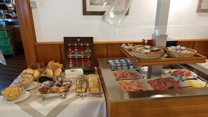 Un bufé con diversos alimentos, incluyendo panes, pasteles y carnes.
