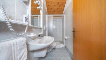 Ein Badezimmer mit Holzboden, einem Waschbecken, einer Toilette und einer Duschkabine.