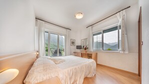 Un dormitorio con una cama grande, un escritorio y vistas al exterior.