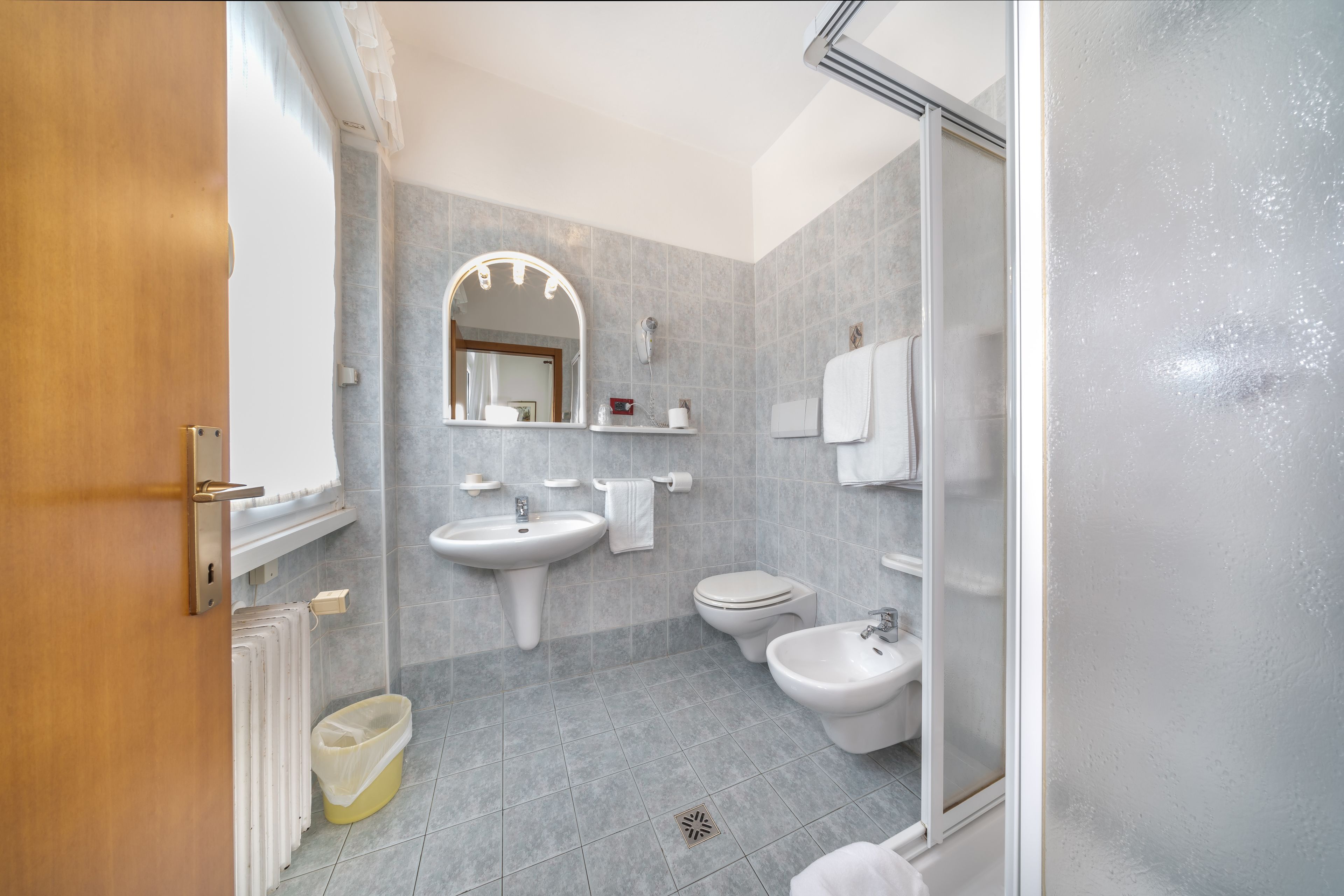 A modern bathroom with a sink, toilet, bidet, and a glass shower enclosure.
