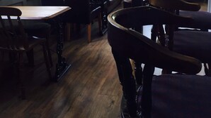 A restaurant interior with wooden tables and chairs, pendant lighting, and large windows allowing natural light. - The New Inn (Beverley)