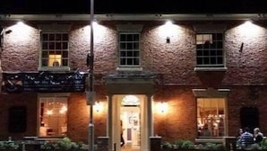 A brick building with a lit entrance and windows, a street lamp, and a crosswalk. - The New Inn (Beverley)
