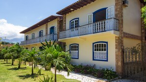 A two-story building with a balcony, stone steps, and a garden with palm trees. - Pousada Eclipse (Paraty)