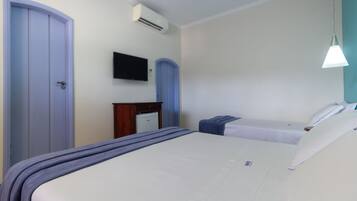 Habitación de hotel con dos camas, un escritorio, televisor y aire acondicionado.