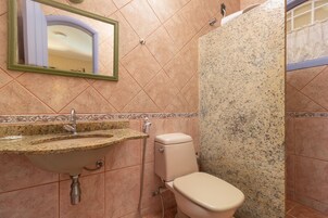 Een badkamer met een granieten wastafel, toilet en douchecabine.