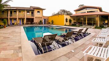 Una piscina con sillones de descanso y un patio con baldosas de piedra.