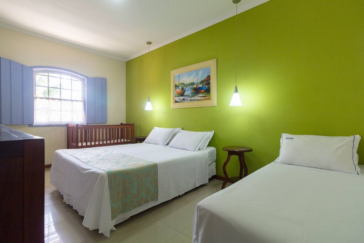 A hotel room with a bed, a desk, a chair, a small table, and a painting on the wall.