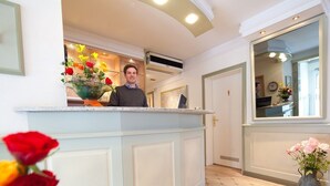 A reception area with a counter, a large mirror, and a wall-mounted air conditioning unit. - Kocks Hotel (Hamburg)