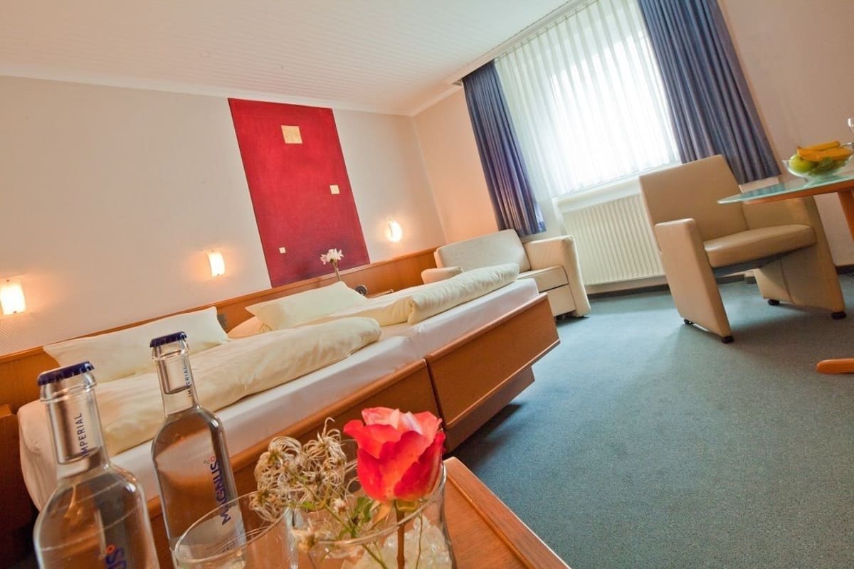 A hotel room with a bed, a desk, and a dining table.