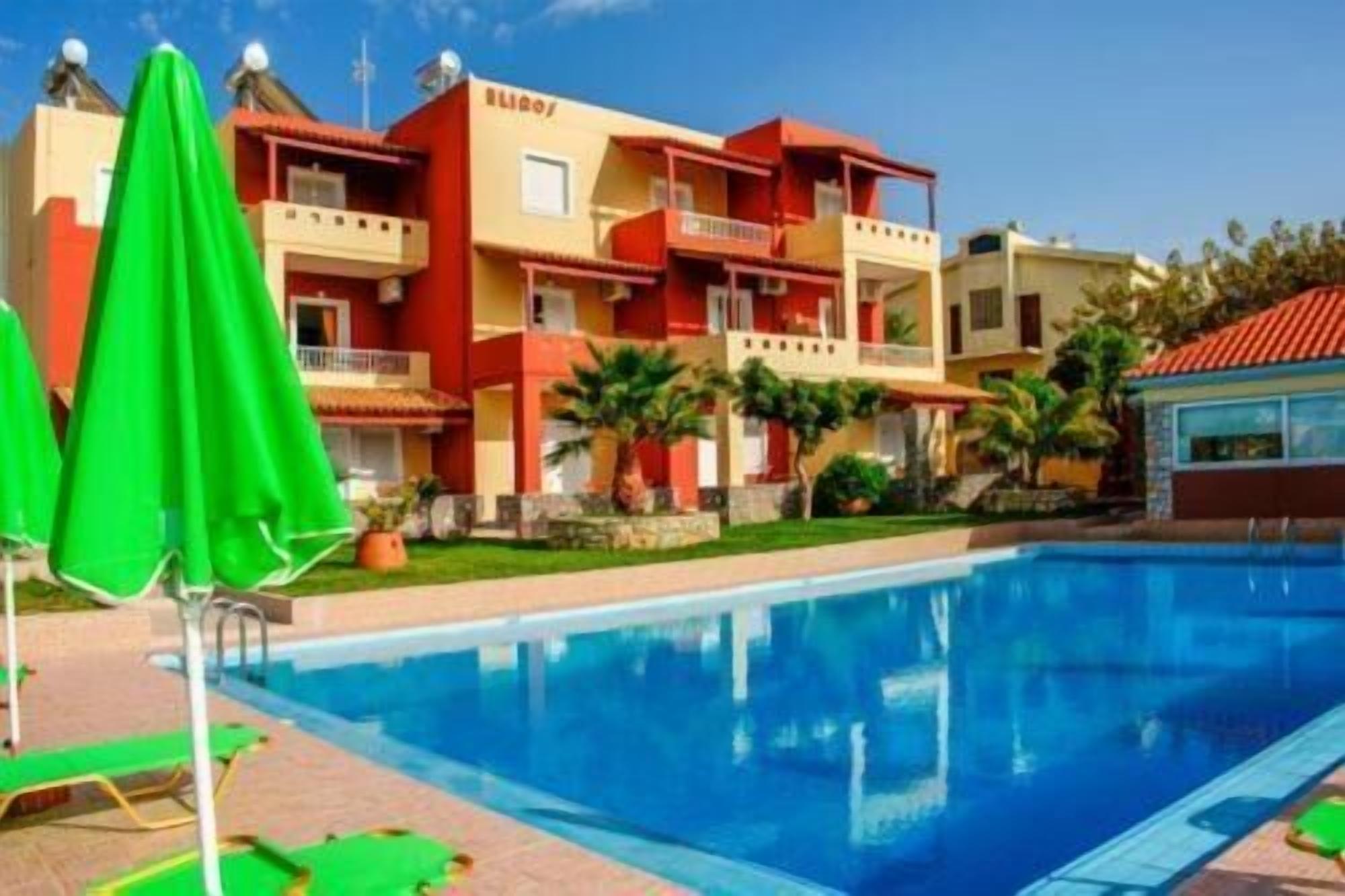 A hotel with a pool, multiple balconies, and a red and yellow facade.