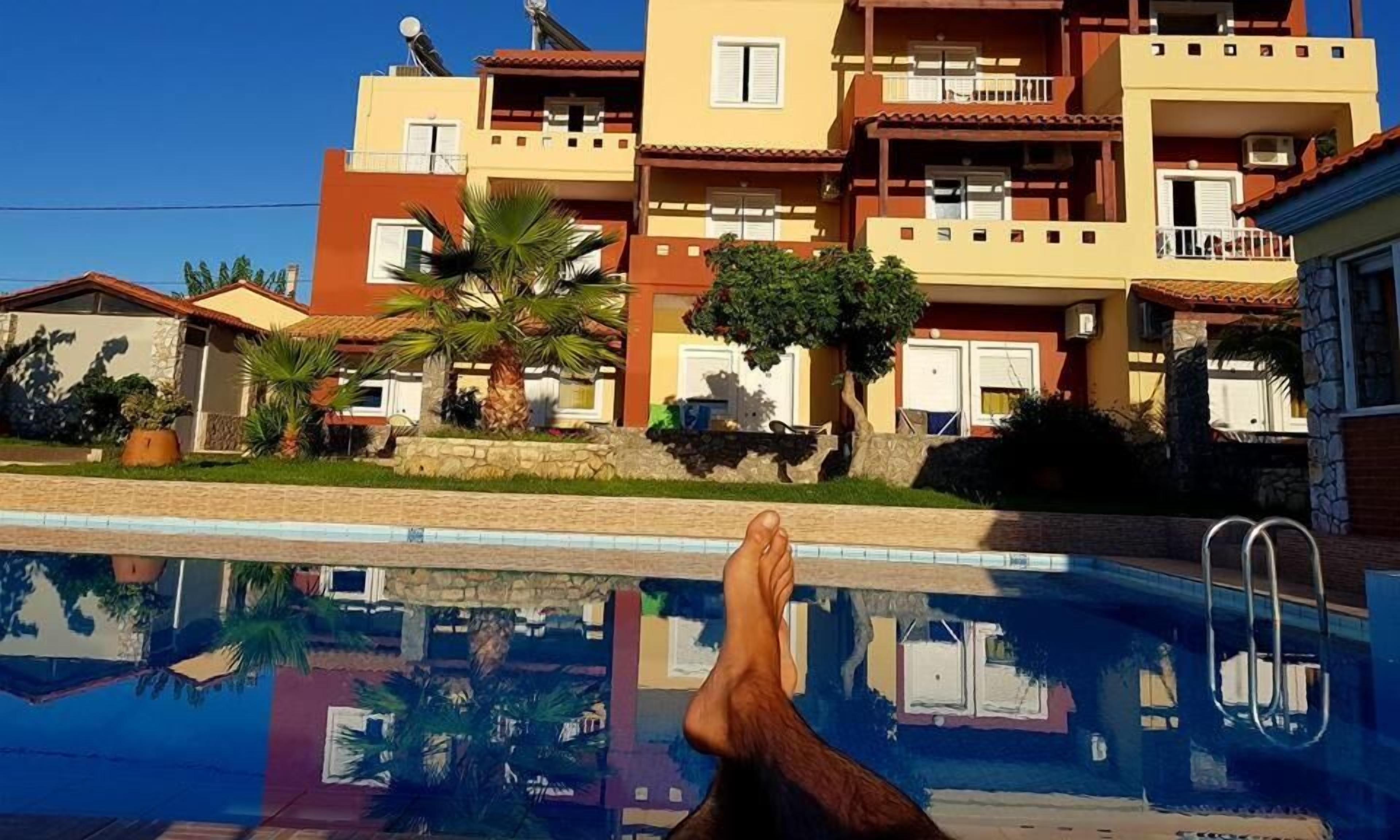 A swimming pool with a reflection of a building and a person's legs.