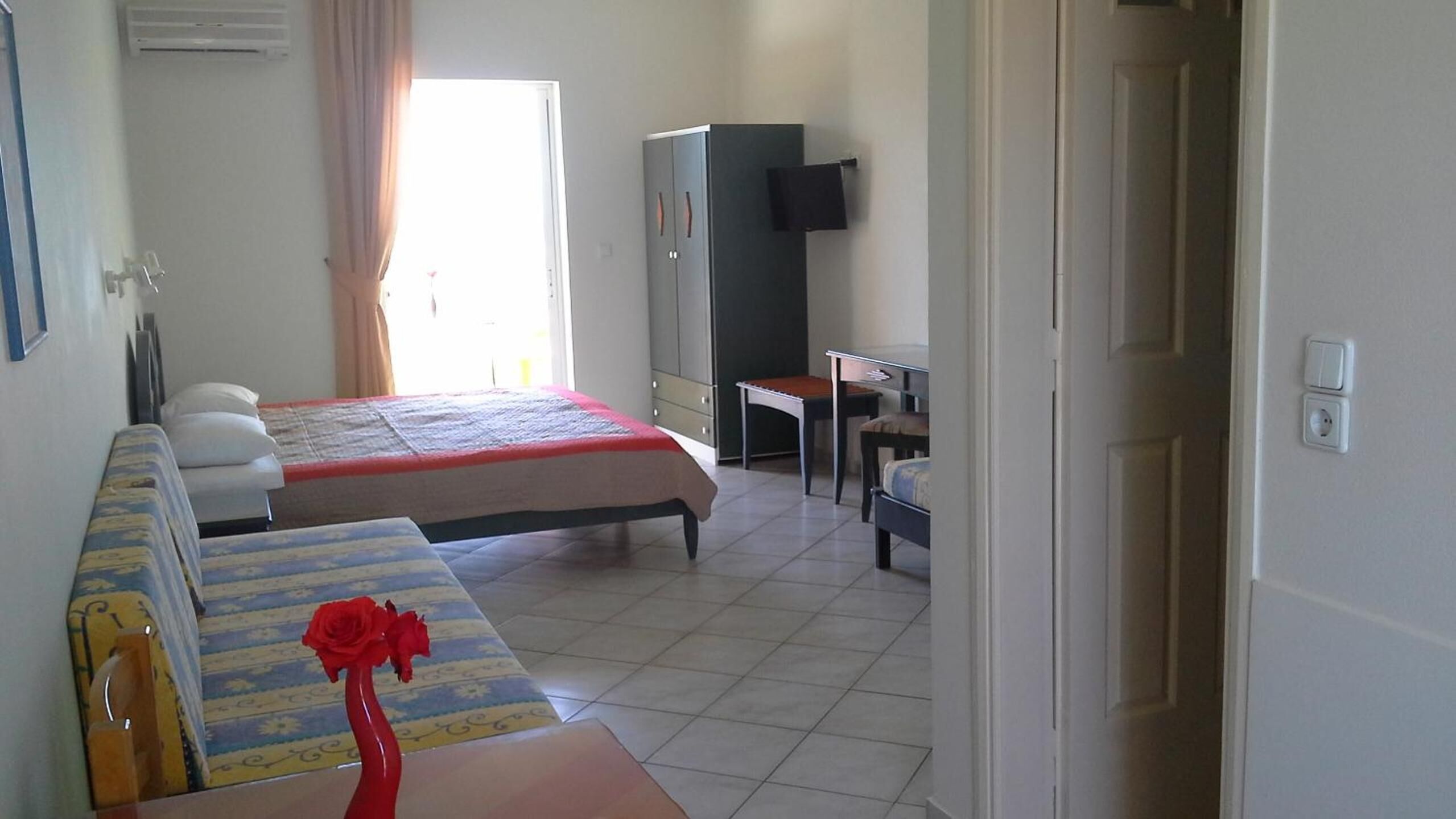 Habitación de hotel con dos camas, un escritorio, una silla, un televisor y un armario.