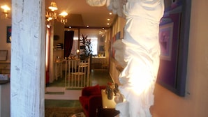 A room with a white statue, a red sofa, and a chandelier. - Solar das Artes Pousada Boutique (Salvador)