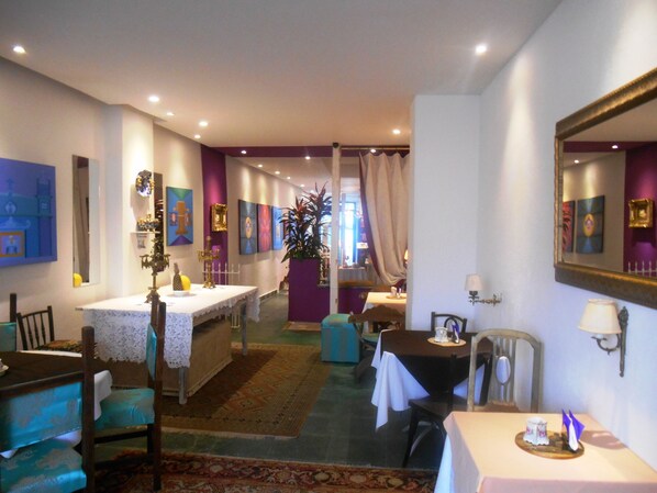 A hotel room with a dining area, a large mirror, and a view of the hallway.