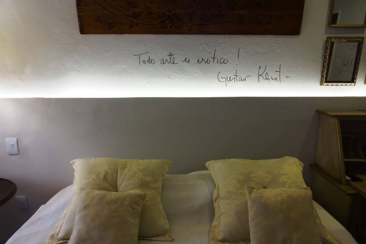 A neatly made bed with two pillows and a wall with a framed quote.