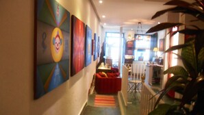 A hallway with colorful artwork on the walls, a red seating area, and a staircase leading to another level. - Solar das Artes Pousada Boutique (Salvador)