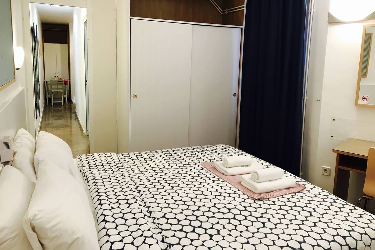 Habitació d'hotel amb llit, armari, escriptori i mirall.