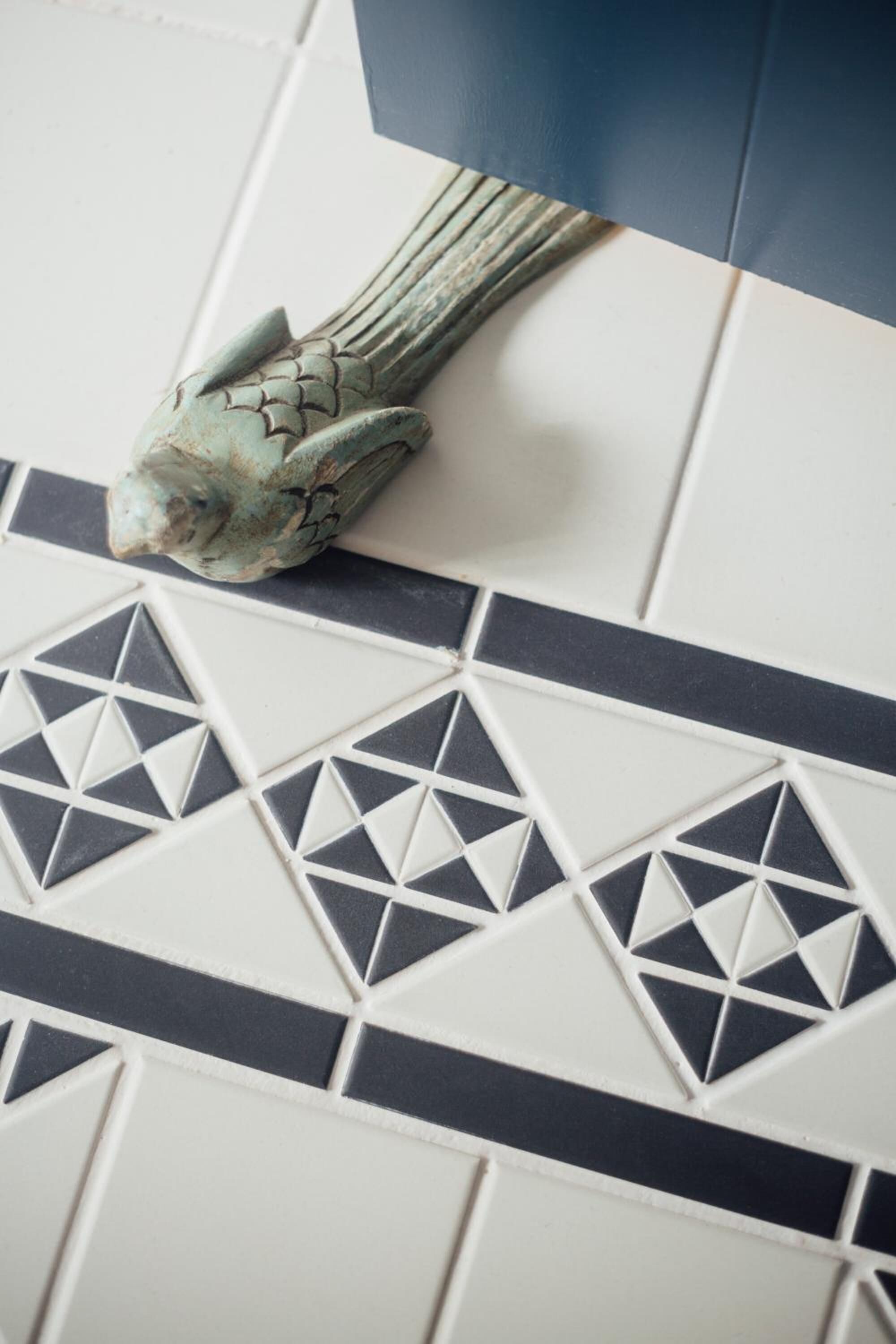 Primer plano de una pared de azulejos con diseños geométricos y una figura decorativa de pez.