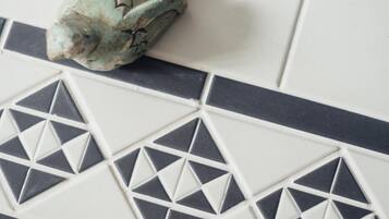 Primer plano de una pared de azulejos con diseños geométricos y una figura decorativa de pez.