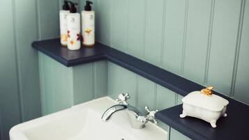 A bathroom with a white sink, a black countertop, and a shelf with toiletries.