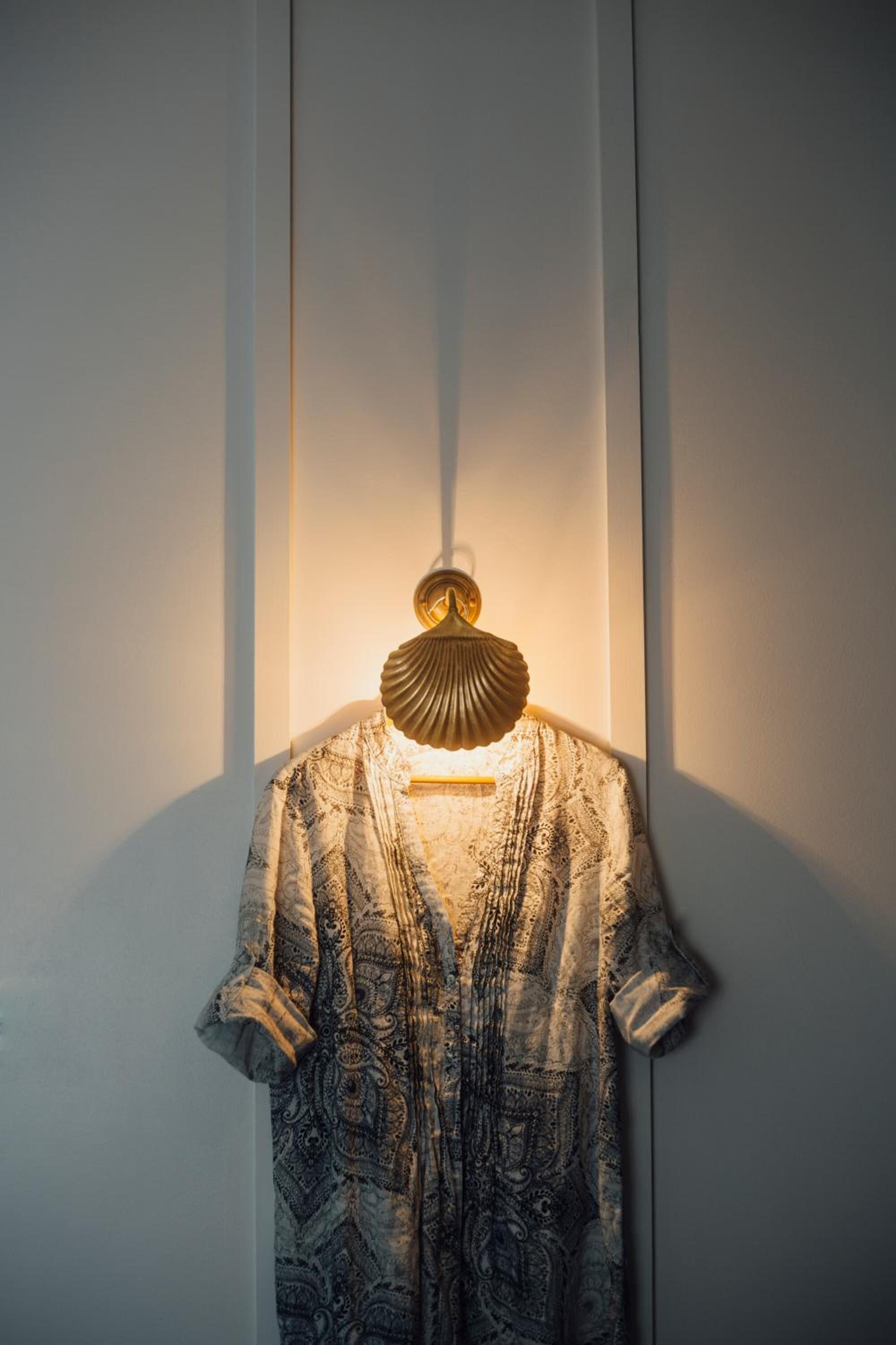 A patterned dress hanging on a wall with a light fixture above it.