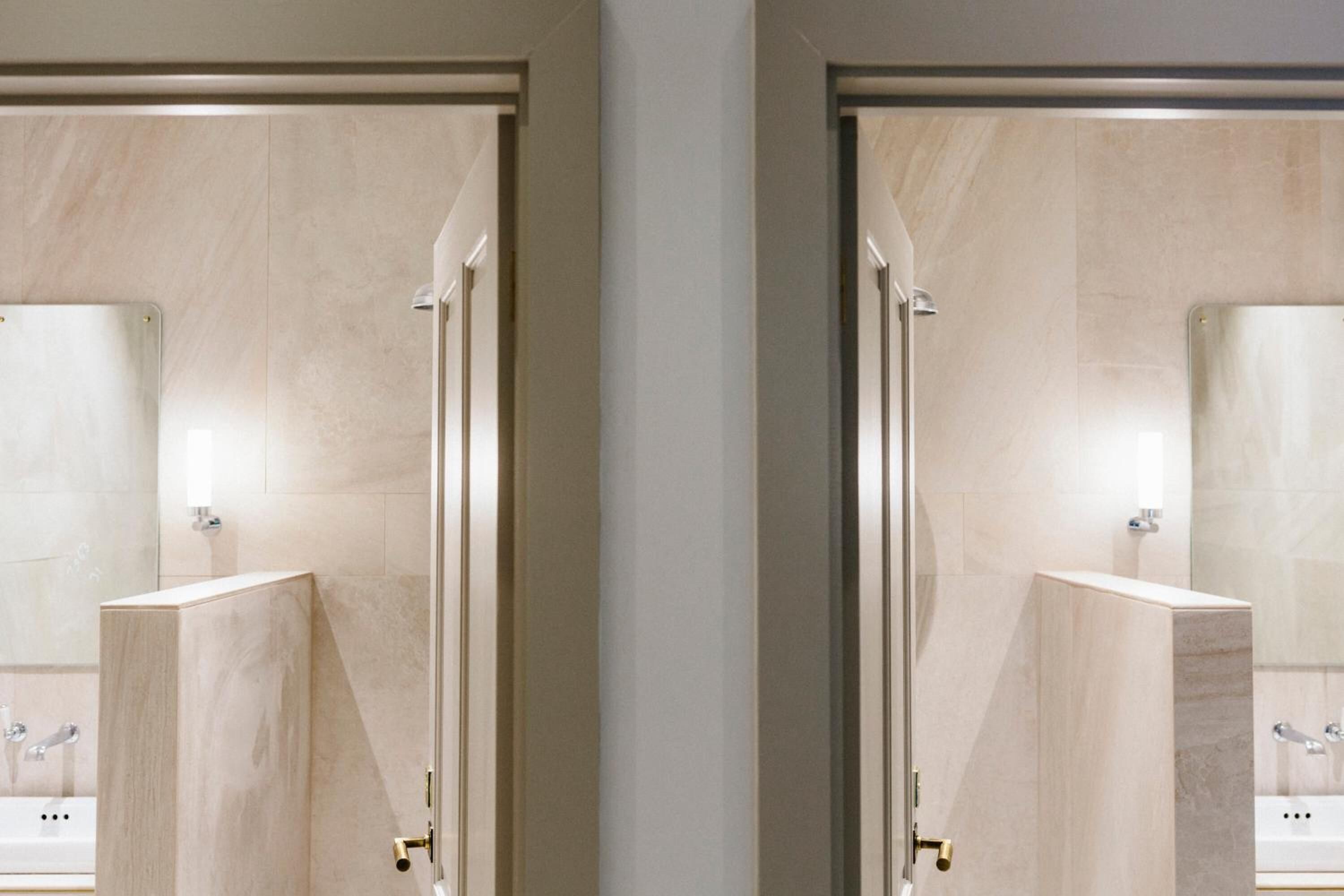 Reflejo en un espejo de un baño moderno con un espejo grande, un lavabo y una zona de ducha.