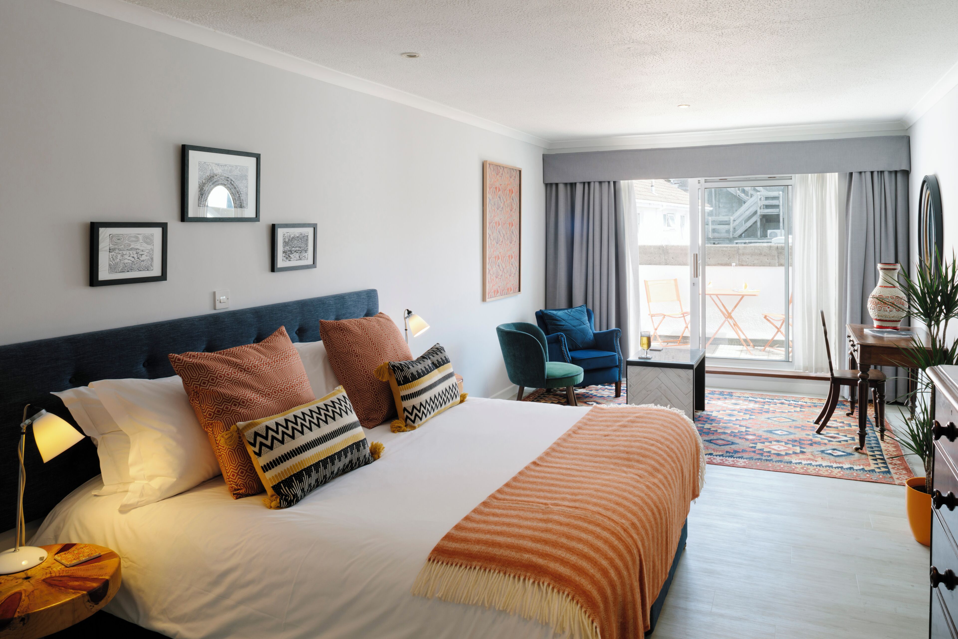 A hotel room with a large bed, a desk, a chair, and a view of the outside.