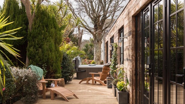 A wooden deck with outdoor furniture, a hot tub, and potted plants. - Merchants Manor (Falmouth)