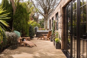 Une terrasse en bois avec des meubles d’extérieur, un jacuzzi et des plantes en pot.