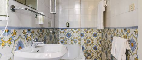A bathroom with a white sink, a shower, and a towel rack.