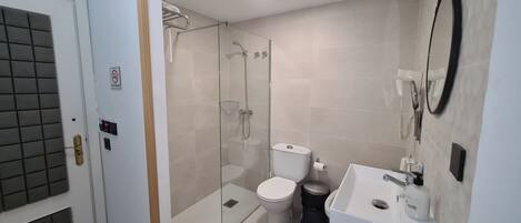 A modern bathroom with a glass-enclosed shower, a toilet, and a sink.