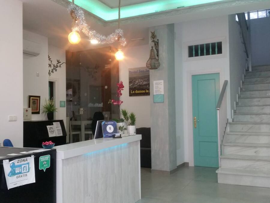 A hotel reception area with a reception desk, a clock, a staircase, and a sign indicating room number 8.