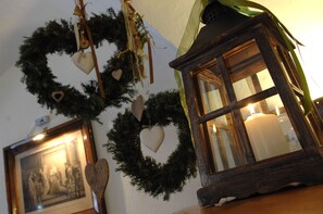 A room with a framed picture, a candle, and a wreath with heart-shaped ornaments. - Excelsior (Cavalese)