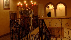 A staircase with ornate metal railings, a fireplace, and a wall-mounted picture. - Excelsior (Cavalese)