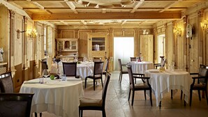 A restaurant with wooden interiors, round tables, and chairs. - Excelsior (Cavalese)
