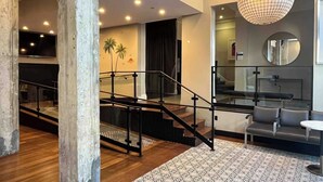 Un interior moderno con una escalera, una sala de estar con asientos y una pared con un mural de palmera.