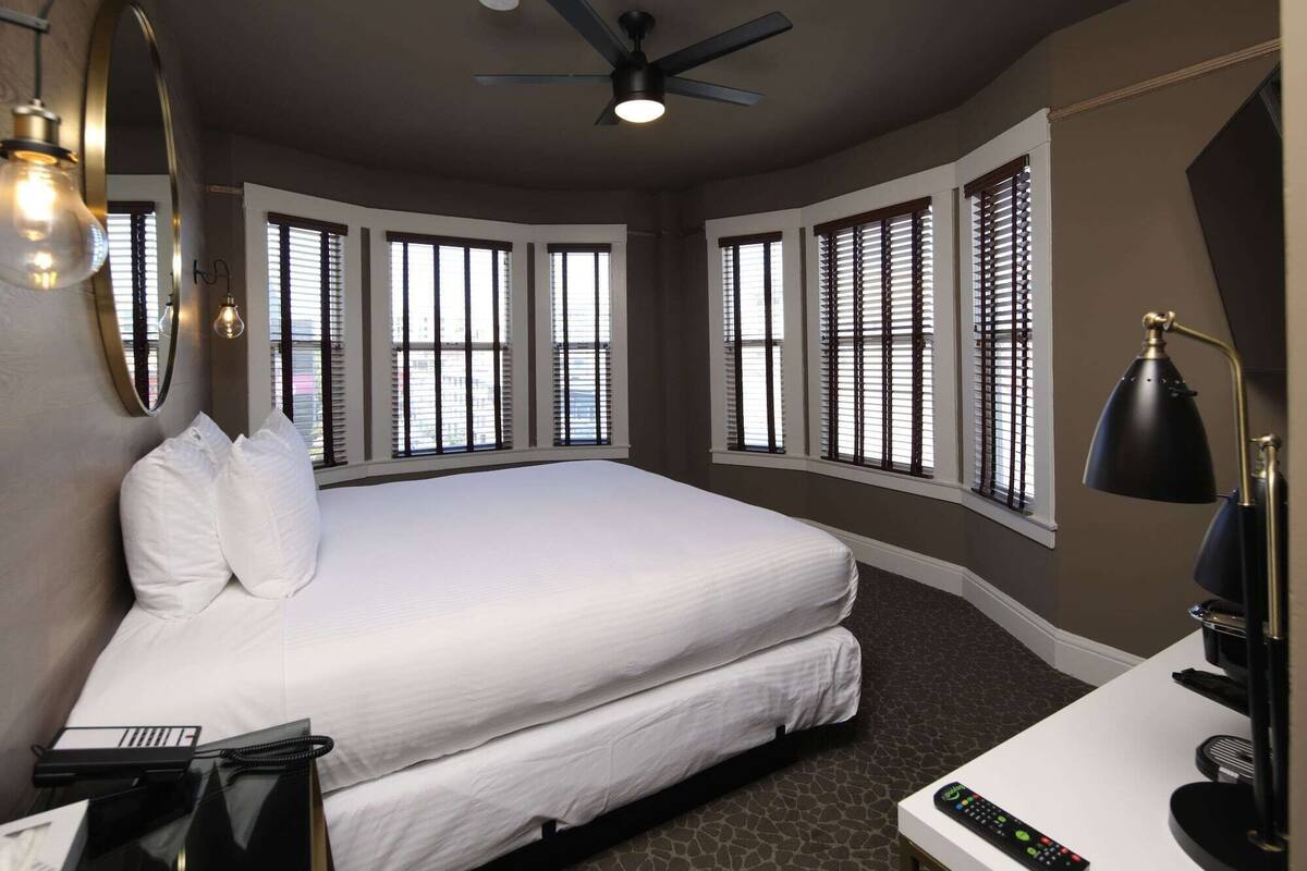 Une chambre d’hôtel avec un grand lit, un bureau avec une lampe, un téléphone et une télécommande.