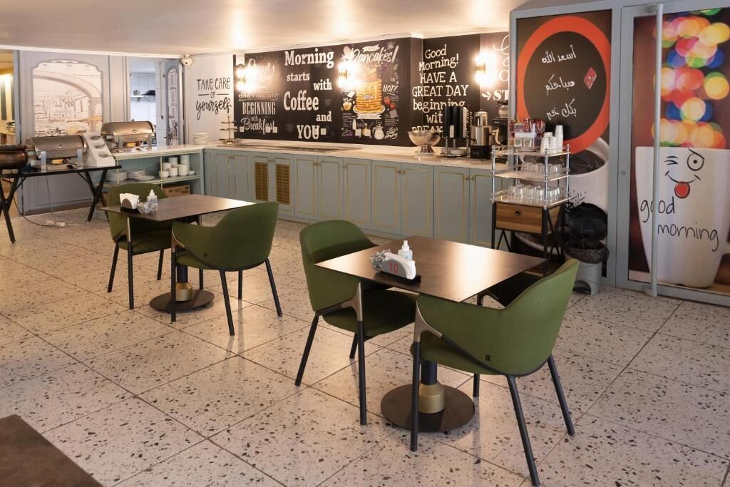 Un café moderne avec des chaises vertes et un comptoir où sont exposés les produits proposés pour le petit-déjeuner.
