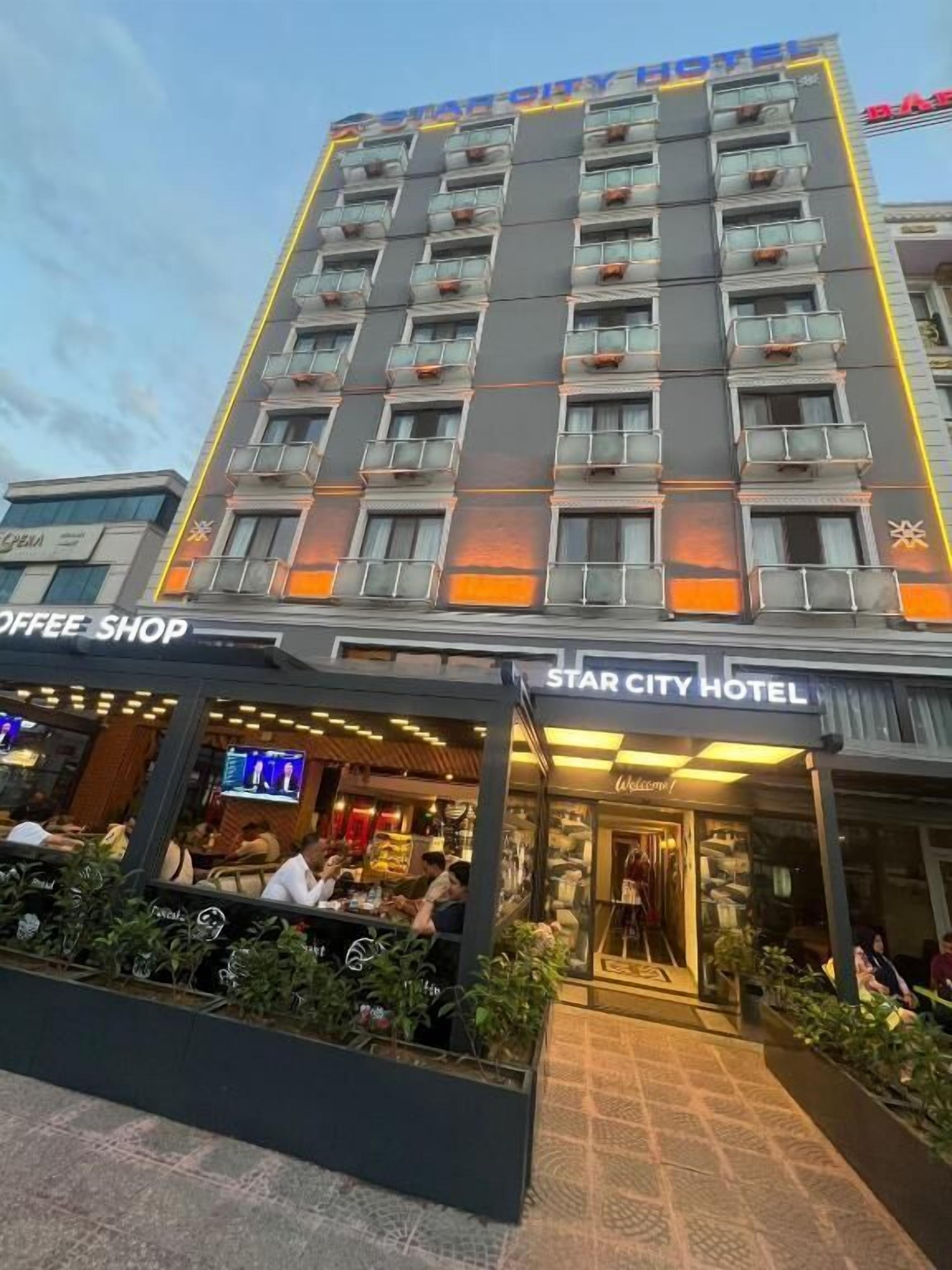 Un hotel con varios pisos, balcones y una cafetería en la fachada.